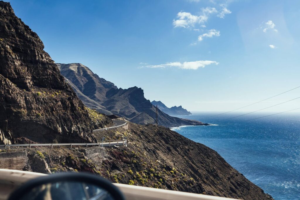 Paisaje costero de Canarias con carretera junto al mar, entorno sostenible
