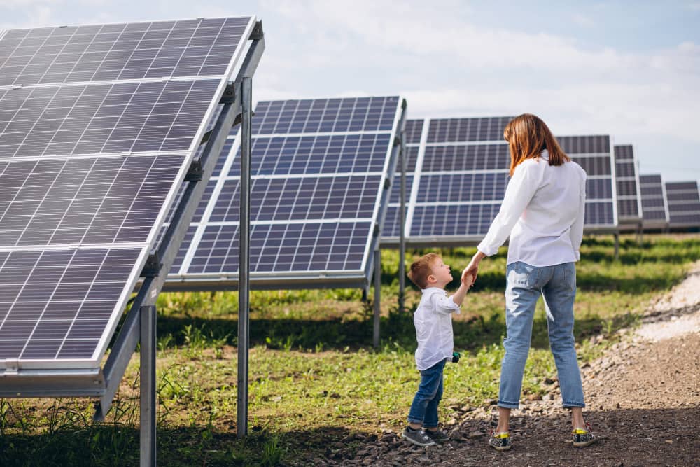 Madre e hijo caminando entre placas solares en huerto solar en Canarias